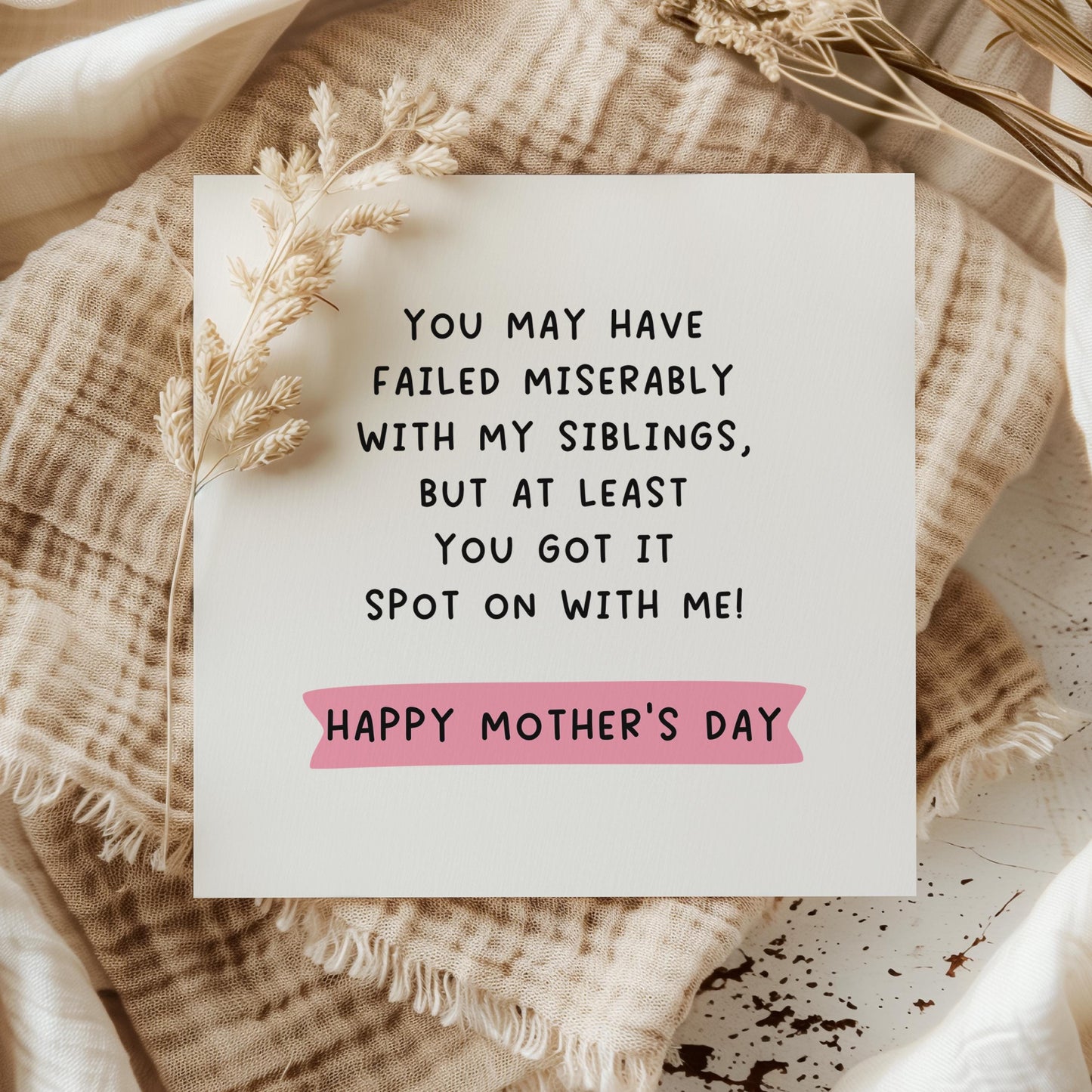 Square white Mother’s Day card with bold black text joke about Mum failing with the siblings but getting it spot on with the sender, pink highlight behind “Happy Mother’s Day”, styled with a brown Kraft envelope on a pale green background.