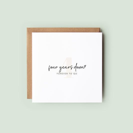 Minimalist 4th anniversary card reading “four years down” and “FOREVER TO GO” with a subtle number 4, shown as a square white 148x148mm (6x6) card with Kraft envelope behind.
