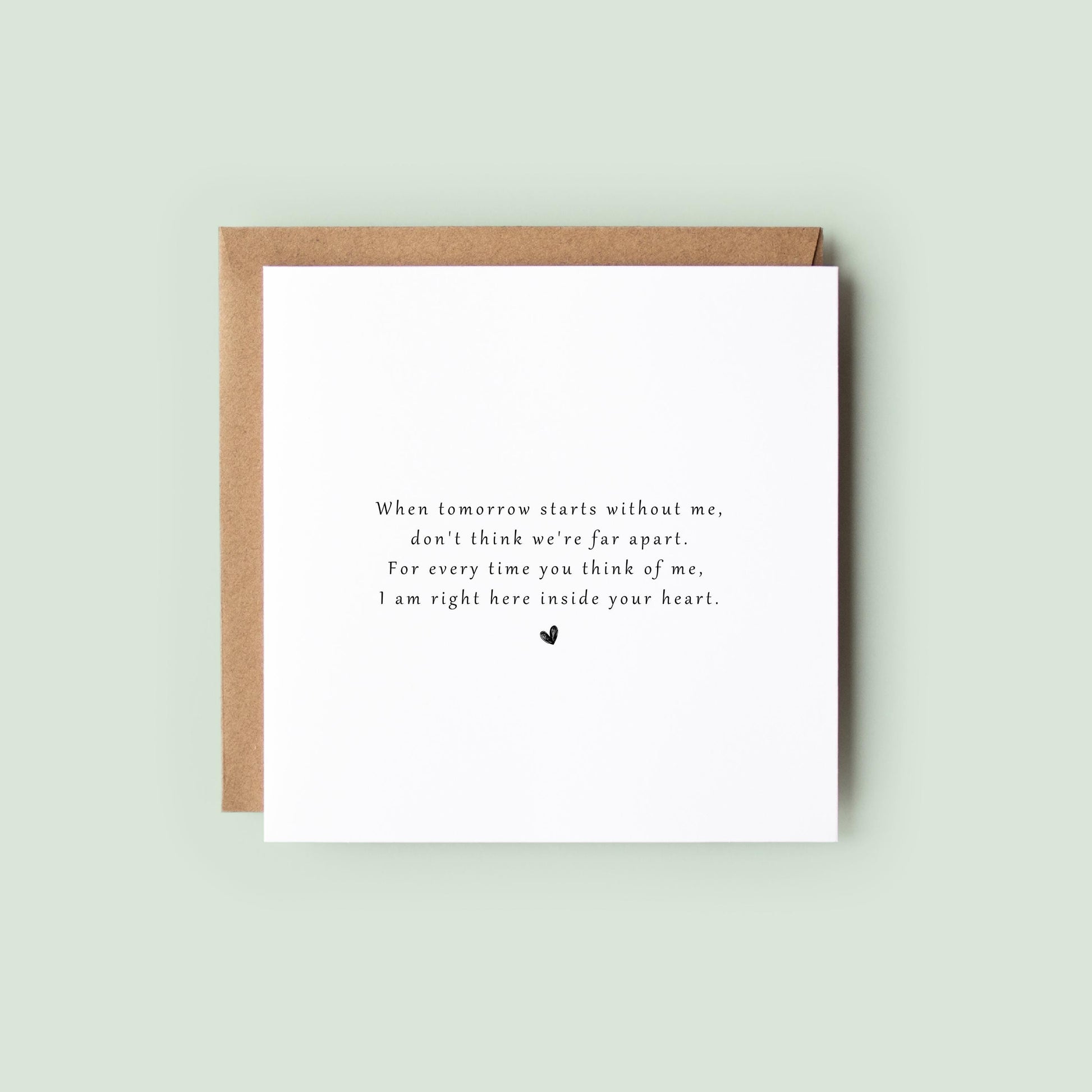 Minimalist sympathy card with heartfelt grief poem printed in black text and a small heart beneath, resting on soft neutral-toned fabric.