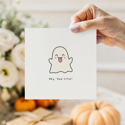 Cute Halloween greeting card featuring a smiling ghost sticking its tongue out with the pun "Hey Boo'tiful!"