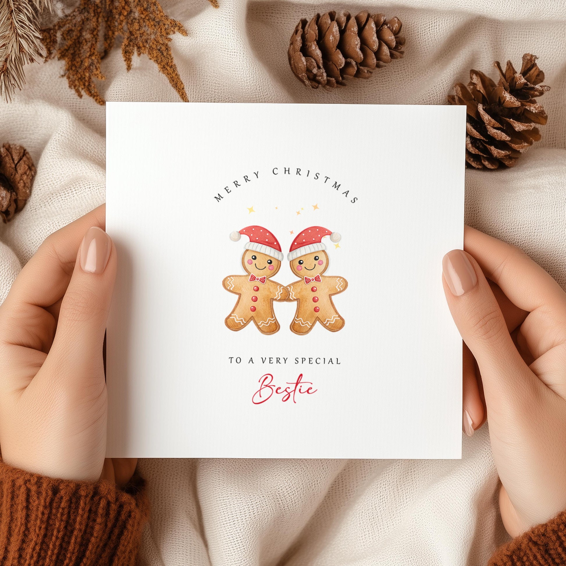 Christmas card with two male gingerbread cookies in Santa hats, captioned “To a very special Bestie” – cosy festive scene with pinecones and blanket.