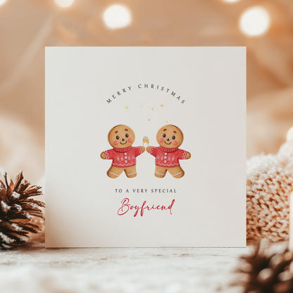 Christmas card with two smiling male gingerbread figures in festive jumpers, captioned “To a very special Boyfriend” – warm and cosy festive background.