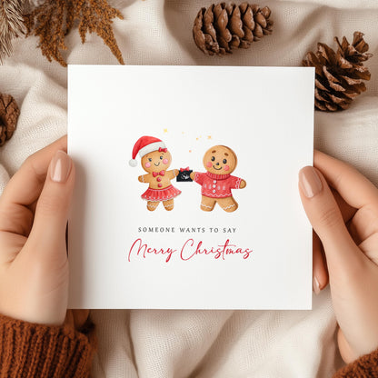 Christmas pregnancy announcement card featuring a festive gingerbread couple holding a baby scan with the message "Someone Wants to Say Merry Christmas."