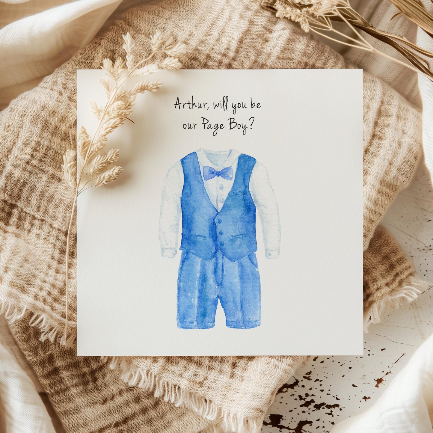 Watercolour page boy proposal card with blue waistcoat and shorts outfit in blue, personalised name above the suit on a neutral background, cute children’s wedding role card.