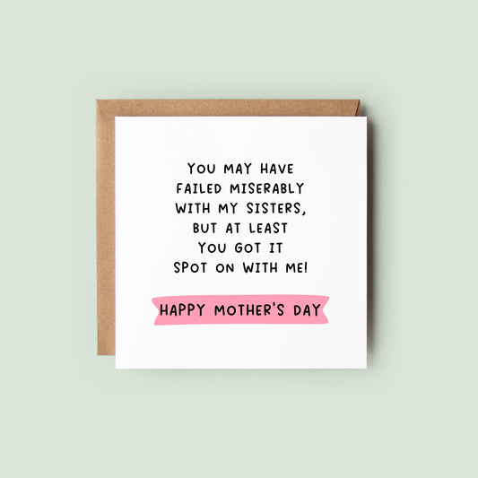 Funny Mother’s Day card with bold black text joke about Mum failing with the sisters but getting it spot on with the speaker, pink banner reading “Happy Mother’s Day” underneath on a simple white square card with kraft envelope.
