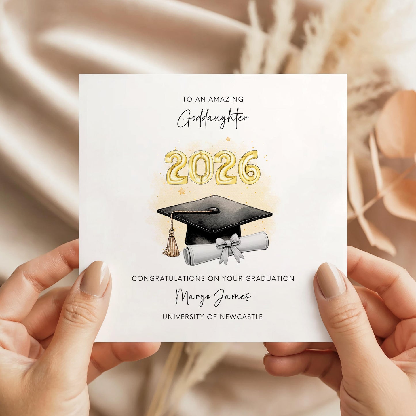 Personalised goddaughter graduation card featuring gold 2026 balloons, graduation cap and diploma scroll. Custom university graduation card with goddaughter title, graduate name, university details and congratulations message.