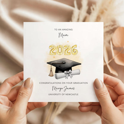 Personalised mum graduation card featuring gold 2026 balloons, graduation cap and diploma scroll. Custom university graduation card with mum title, graduate name, university details and congratulations message.
