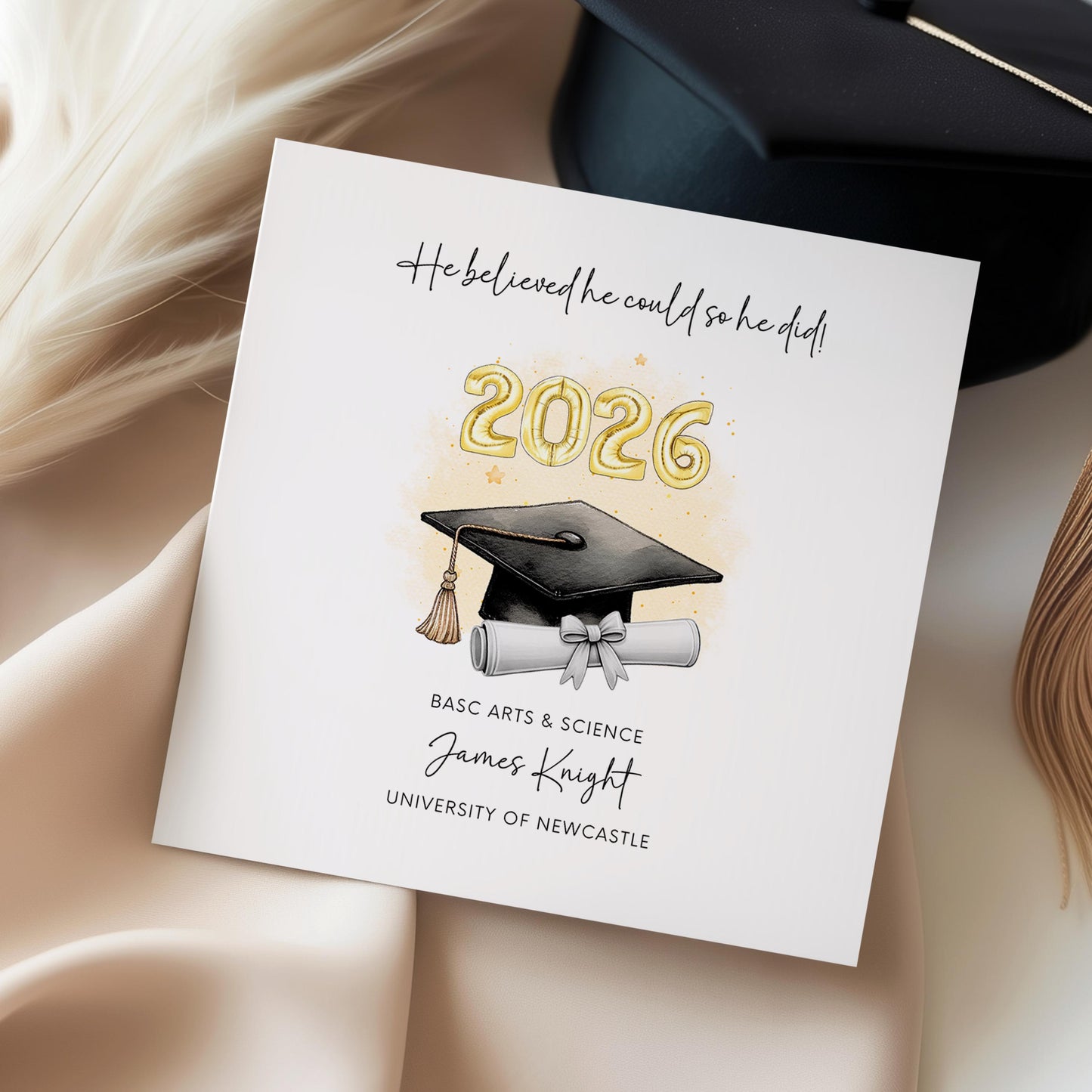 Personalised graduation card for him featuring gold 2026 balloons, graduation cap and diploma scroll. Custom graduate card with degree title, graduate name, university and motivational graduation quote.