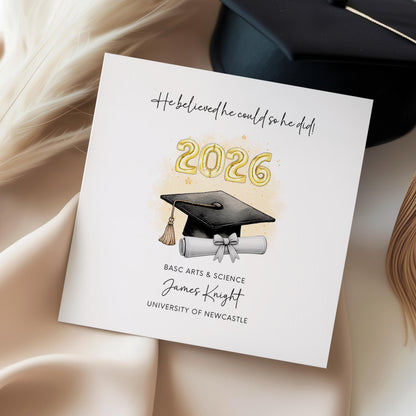 Personalised graduation card for him featuring gold 2026 balloons, graduation cap and diploma scroll. Custom graduate card with degree title, graduate name, university and motivational graduation quote.