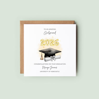 Personalised girlfriend graduation card featuring gold 2026 balloons, graduation cap and diploma scroll. Custom university graduation card with girlfriend title, graduate name, university details and congratulations message.