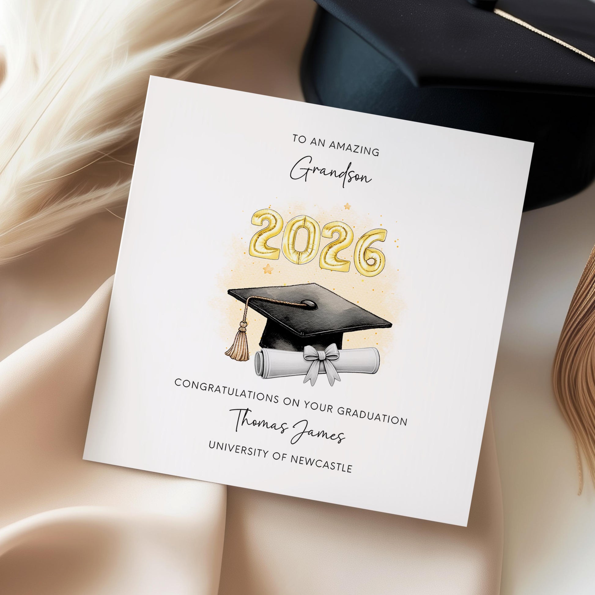 Personalised grandson graduation card featuring gold 2026 balloons, graduation cap and diploma scroll. Custom university graduation card with grandson title, graduate name, university details and congratulations message.