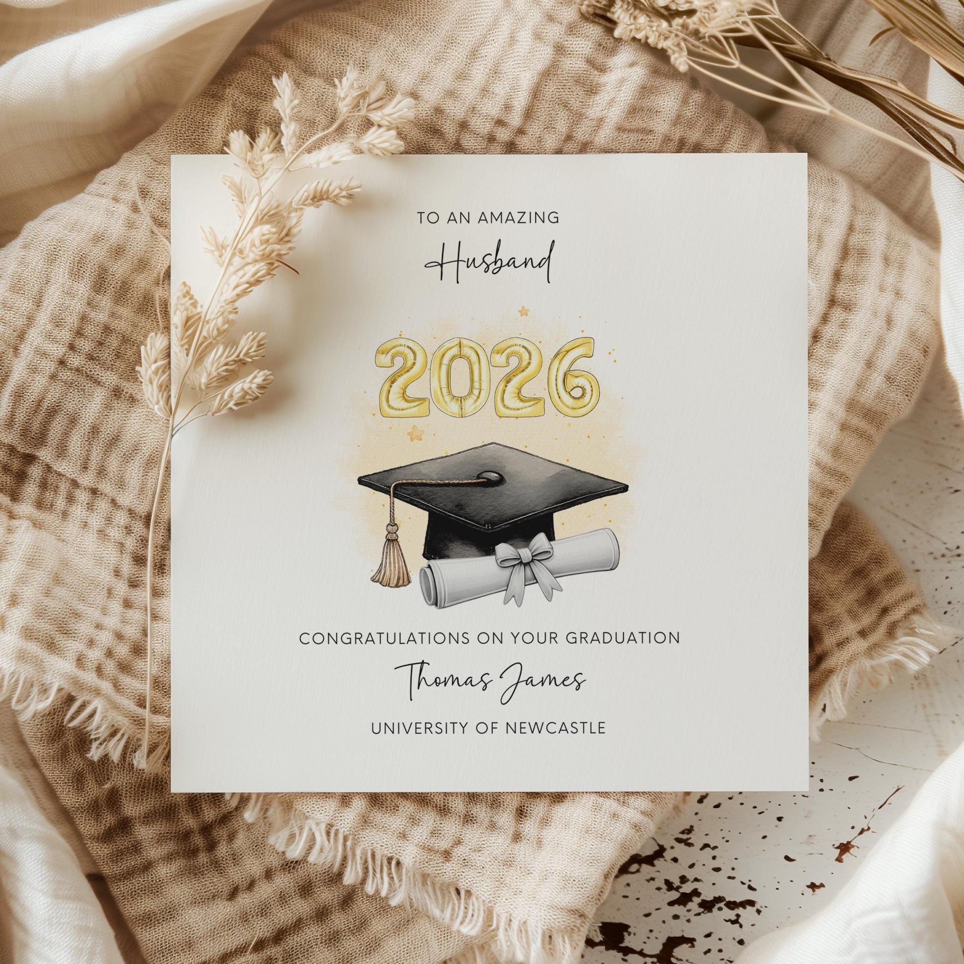 Personalised husband graduation card featuring gold 2026 balloons, graduation cap and diploma scroll. Custom university graduation card with husband title, graduate name, university details and congratulations message.