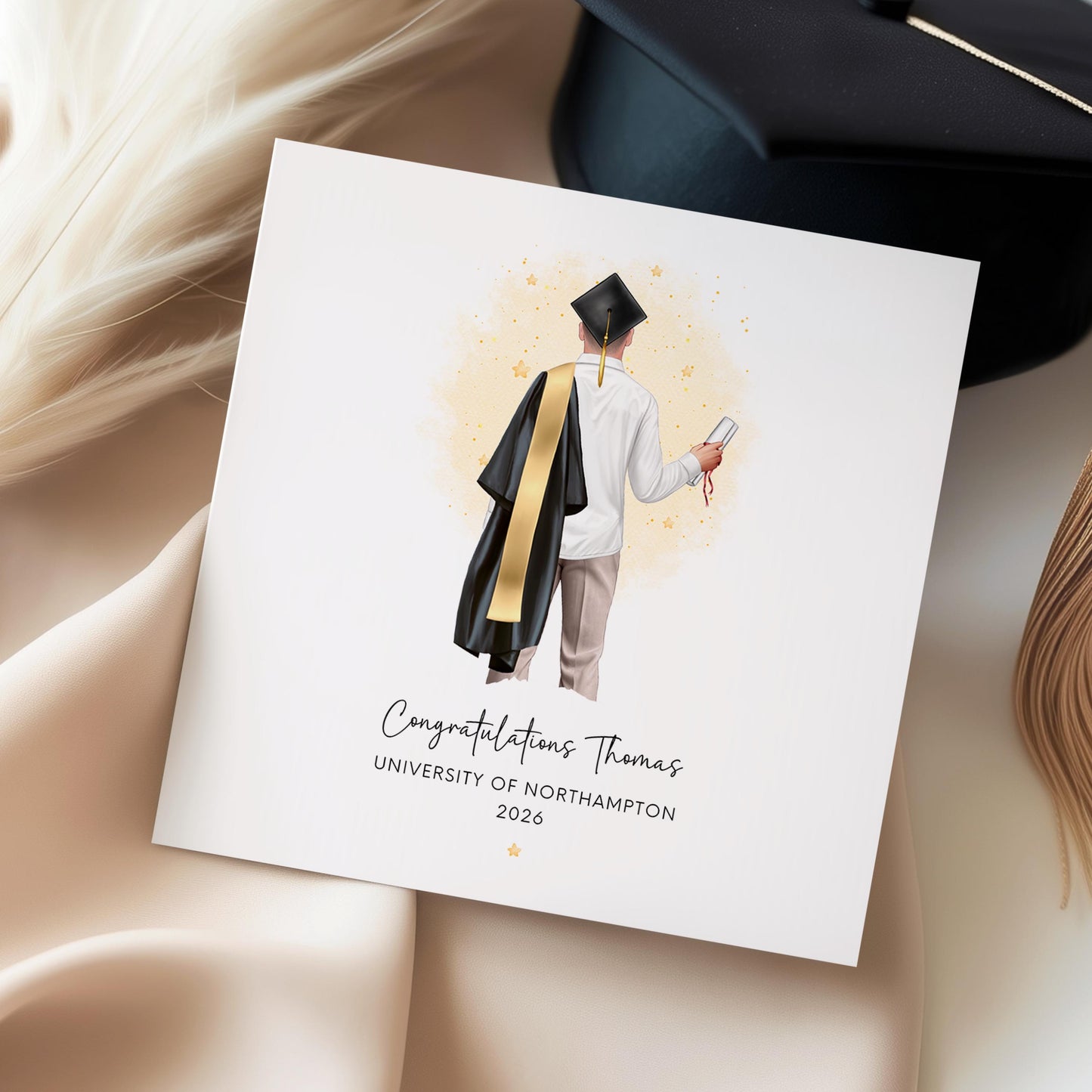 Personalised graduation card featuring a custom male graduate illustration with personalised hair, clothing, robe and sash colours, holding a diploma with university details and graduation year.