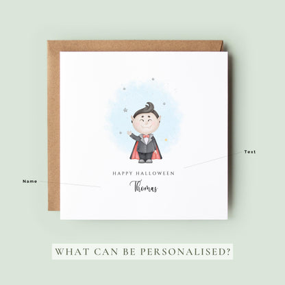 Personalised Halloween card featuring a cute smiling vampire in a cape with a custom name underneath and the words "Happy Halloween" on a white greeting card.