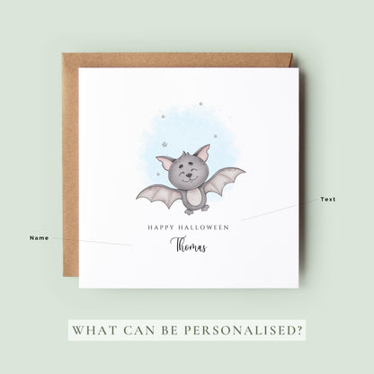 Personalised Halloween card featuring a cute smiling watercolour bat with a custom name underneath and the words "Happy Halloween" on a white greeting card.