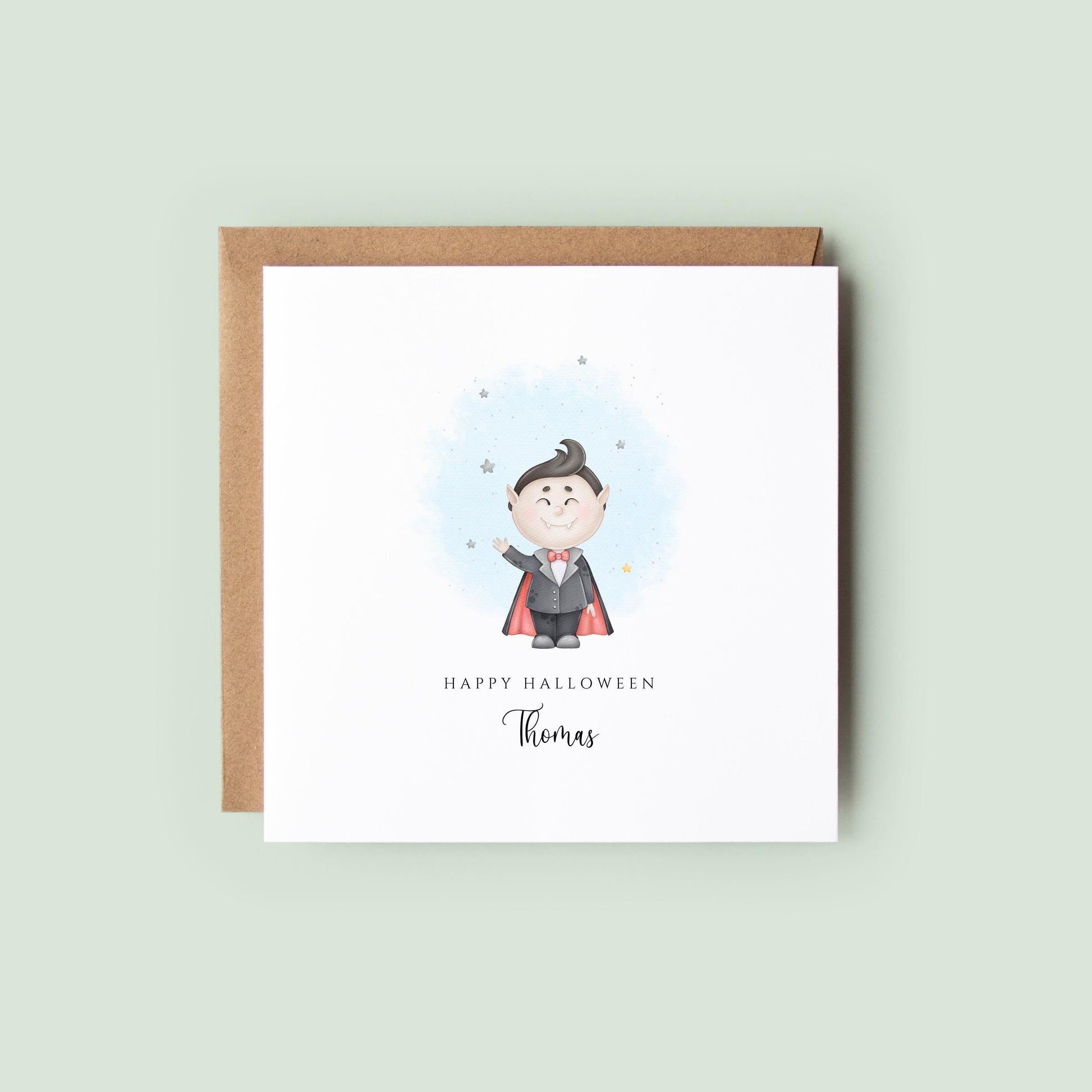 Personalised Halloween card featuring a cute smiling vampire in a cape with a custom name underneath and the words "Happy Halloween" on a white greeting card.