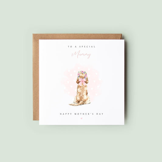 Personalised pet Mother’s Day card from the dog or cat with a watercolour pup sitting in a pastel flower crown and pink bow, with soft heart background and “To a special Mummy – Happy Mother’s Day”, shown as a square 148x148mm (6x6) card with Kraft envelope behind.